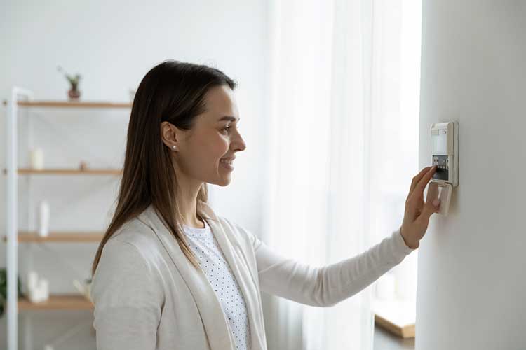 woman touching wall digital thermostat
